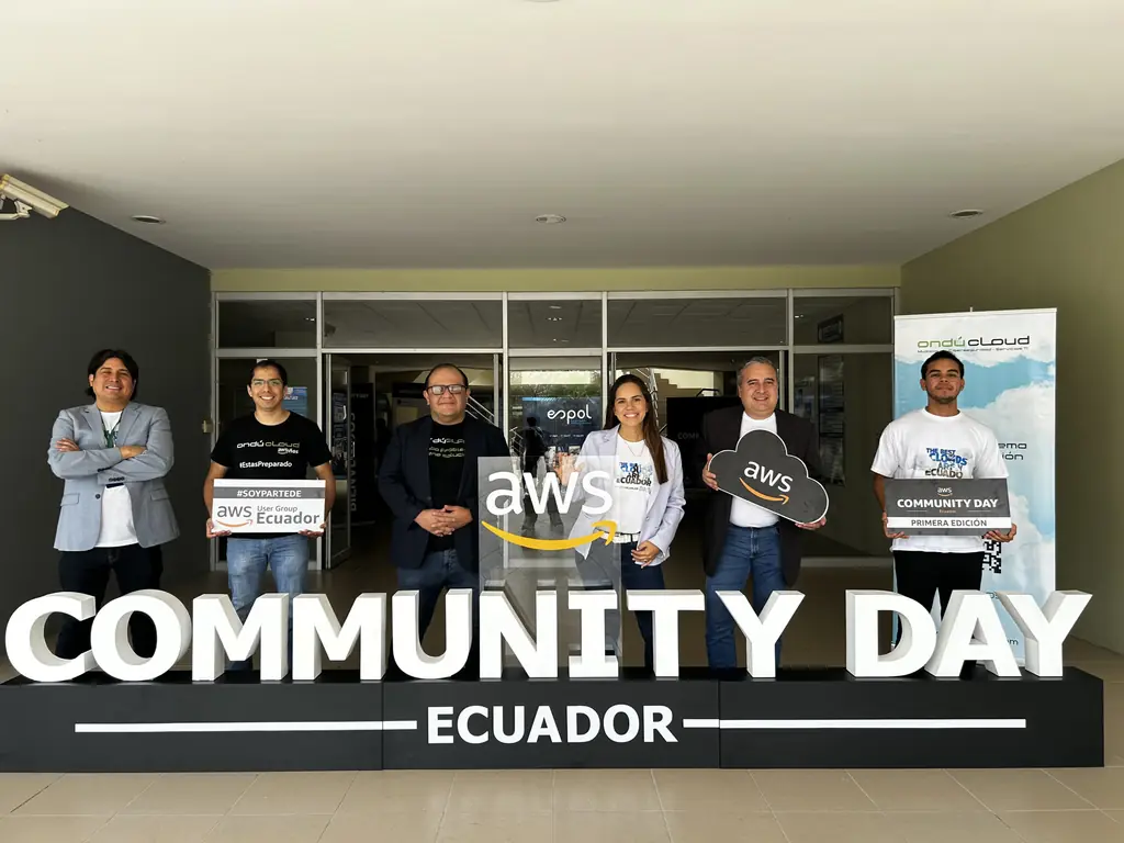 Organizadores de AWS User Group Ecuador junto al letrero de AWS Community Day Ecuador