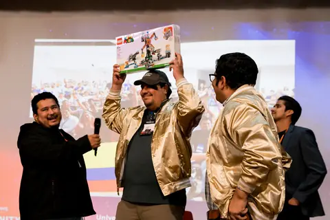 Alexis Polo entrega un premio a un asistente en el escenario del AWS Community Day Ecuador 2025