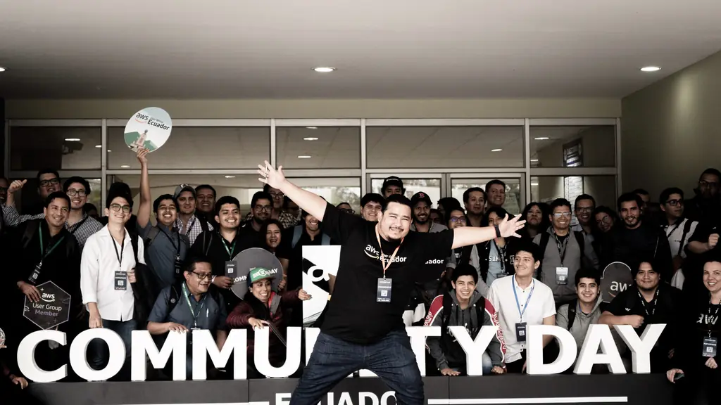Alexis Polo, líder de AWS User Group Ecuador, celebra con los asistentes frente al letrero de AWS Community Day Ecuador