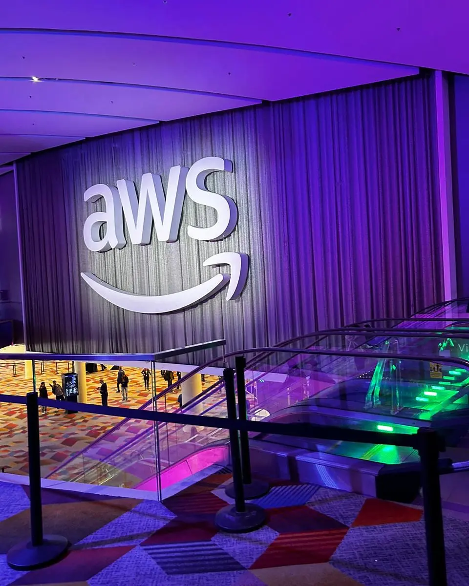 Logo gigante de AWS iluminado en morado en el hall de AWS re:Invent en Las Vegas