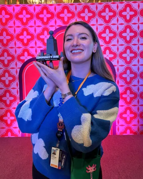 Integrante de AWS User Group Ecuador sonríe con la réplica del monumento de AWS Community Day Ecuador en AWS re:Invent