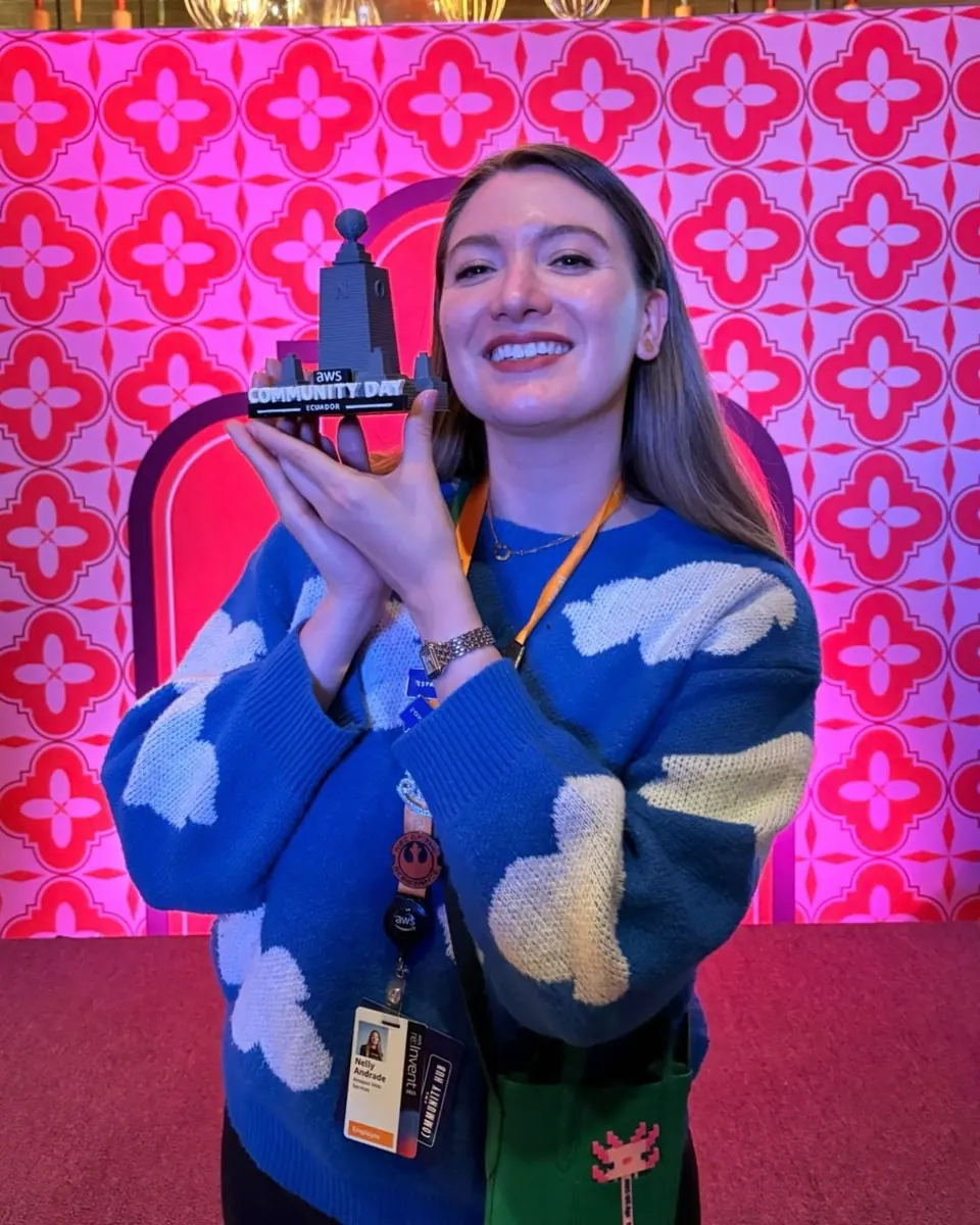 Integrante de AWS User Group Ecuador sonríe con la réplica del monumento de AWS Community Day Ecuador en AWS re:Invent